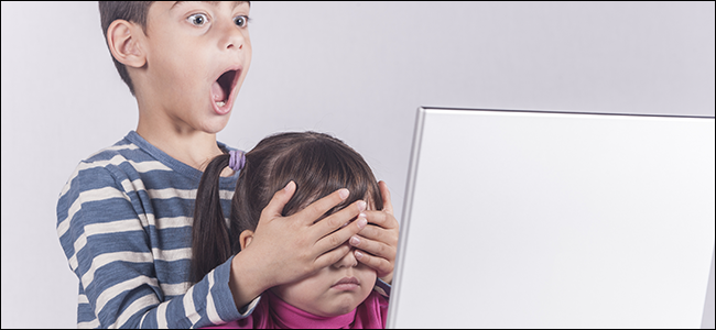 Un niño cubre los ojos de su hermana frente a la computadora.
