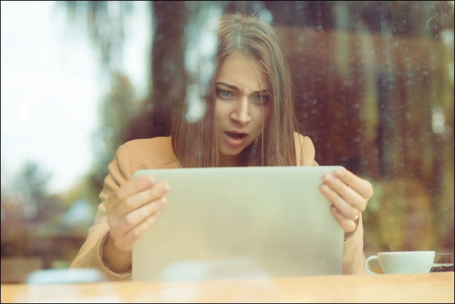 Una dama sorprendida sostiene una pantalla de computadora portátil.