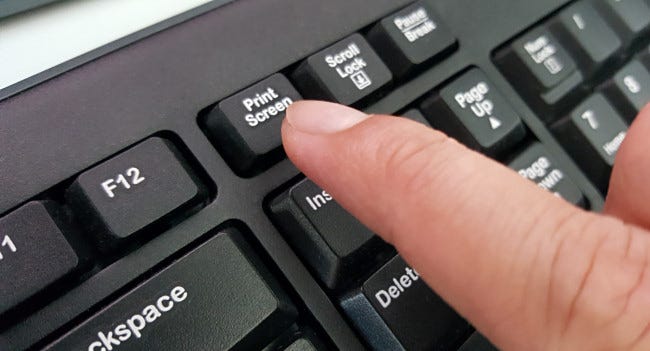Un dedo presiona la tecla Imprimir pantalla en el teclado.