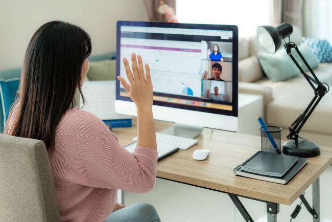 Una mujer saluda a una computadora durante una videollamada.